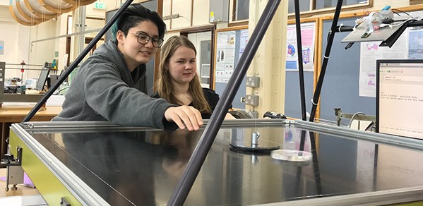 Students during one of the new practical experiments in mechanics. Here they are observing the orbital motion of a puck on an air table.