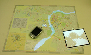 An augmented map showing the flooded River Cam. The image browser to the right shows views corresponding to locations and different stages of the flood, while the PDA to the left controls a helicopter unit.