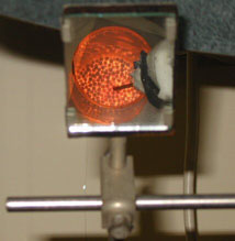 Photograph from above showing red-hot ceramic material. The flame sits deep inside the solid.