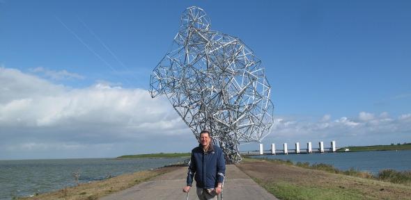 Antony Gormley in front of his sculpture