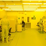 Researchers working in a cleanroom. The image has an overall yellow tone to it