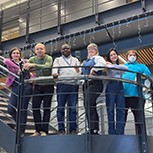 Members of the research team standing in line on the balcony of a stairway with one of them holding the award