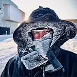 A head and shoulders shot of Dr Shaun Fitzgerald in a snow hood standing amongst lots of snow. His hood is covered in frost