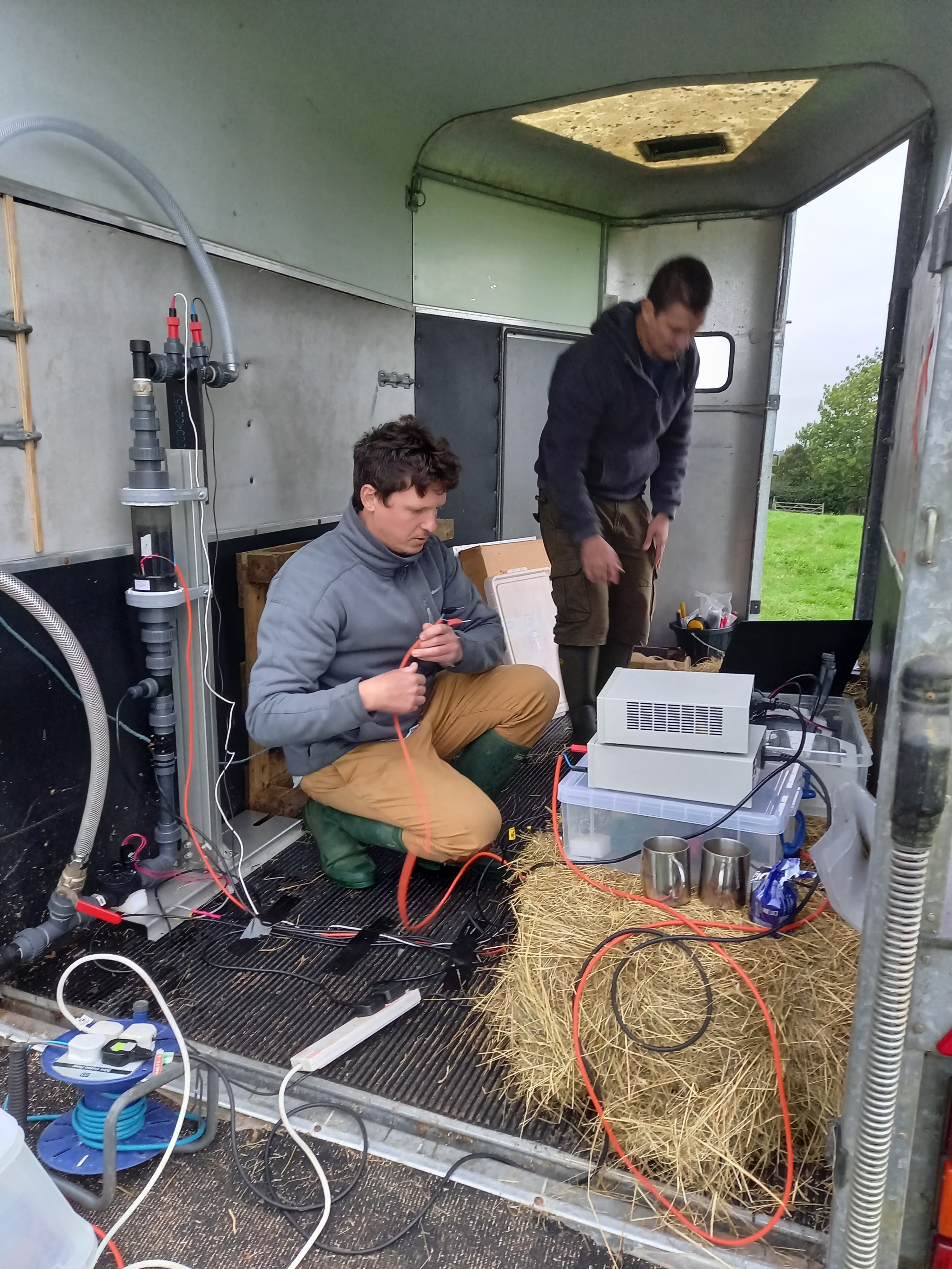 Tom monitoring an early DCC PV-solar electro-chlorinator prototype in a cattle watering borehole in a rainy field in Devon. The aim was to test the ability of the equipment to treat water at its limits – low sunlight and soft water. Colleague Tom Law in the background is also ex. CUED and was a student of Ann Dowling on the Silent Aircraft Initiative. October 2022